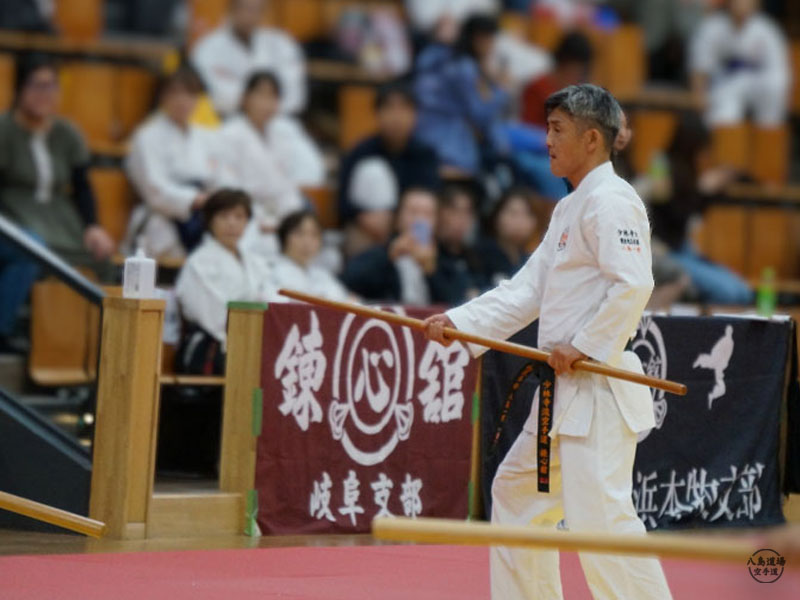 指導者の八島が大会で棒術の演武を行う場面